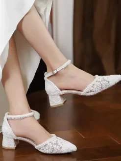 Chaussures de mariée ivoire à bout pointu talon compensé et bride cheville ornées de dentelle.