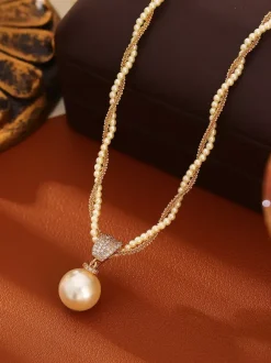 Collier élégant de perles à plusieurs rangs serti de strass carré et orné d'une perle en forme de larme. Breloque en perle.