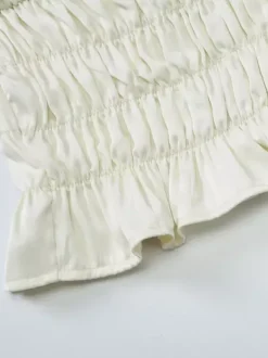 Ensemble deux pièces abricot chic plissé idéal pour les vacances avec bretelles et col à volants jupe sans manches à volants.
