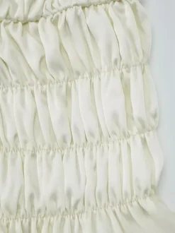 Ensemble deux pièces abricot chic plissé idéal pour les vacances avec bretelles et col à volants jupe sans manches à volants.