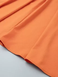 Ensemble deux pièces jupe et haut orange à boutons rétro style resort en lin col V sans manches.