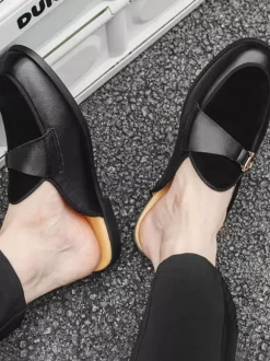 Mocassins noirs à bout rond avec détails métalliques et talon ouvert