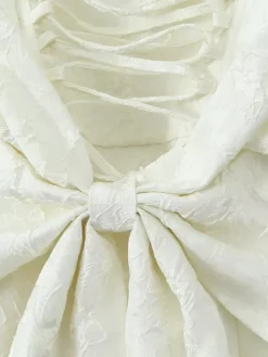 Robe blanche chic à n艙uds sculptants et sans manches col carré idéale pour une soirée romantique.