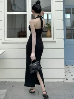 Robe longue noire élégante dos nu à lacets sans manches et décolleté licou idéale pour une soirée en amoureux.