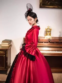 Robe longue rouge rétro victorienne à manches longues évasées style rococo avec coiffe.