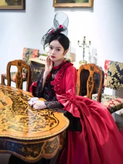 Robe longue rouge rétro victorienne à manches longues évasées style rococo avec coiffe.
