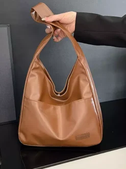 Sac bandoulière hobo minimaliste en similicuir souple grand format en forme de U à porter sous l'aisselle.