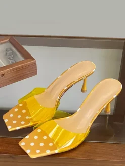 Sandales jaunes à talons hauts transparentes à bout ouvert et sans talon.