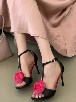 Sandales noires de soirée en satin à bout ouvert et détails floraux en forme de T à talons hauts.