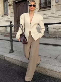 Veste blazer péplum sans manches à col en V et boutonnage nacré à une rangée de boutons.